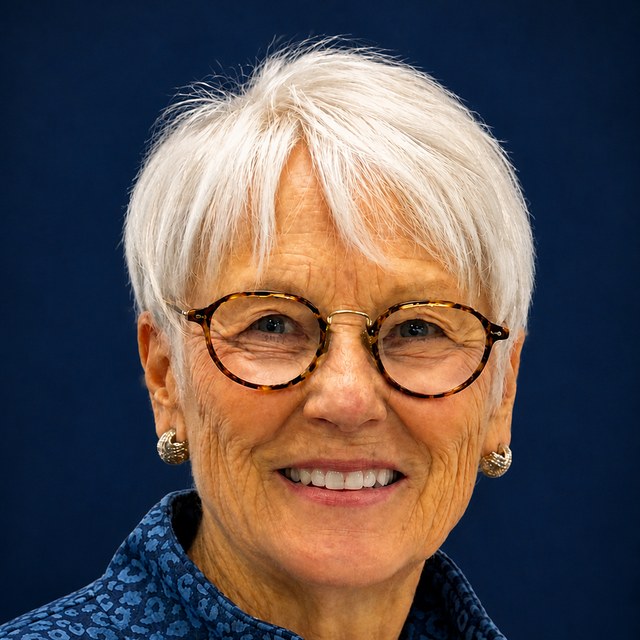 Judith Kennedy Lavender, smiling, in round tortoiseshell glasses